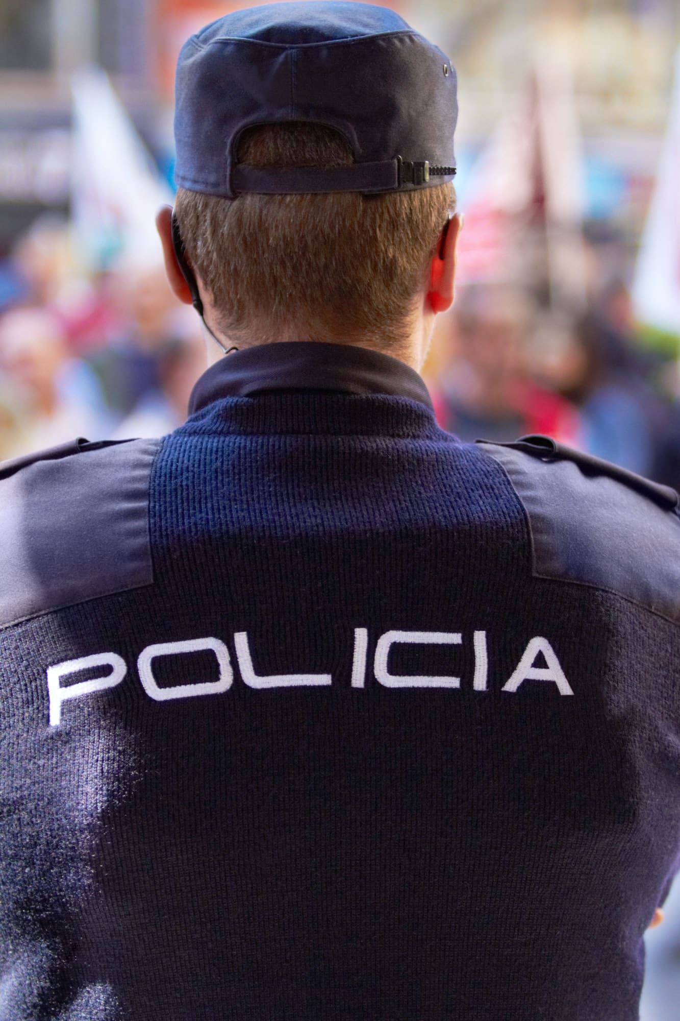 Rearview shot of a policeman wearing a uniform with the word, POLICIA on the back